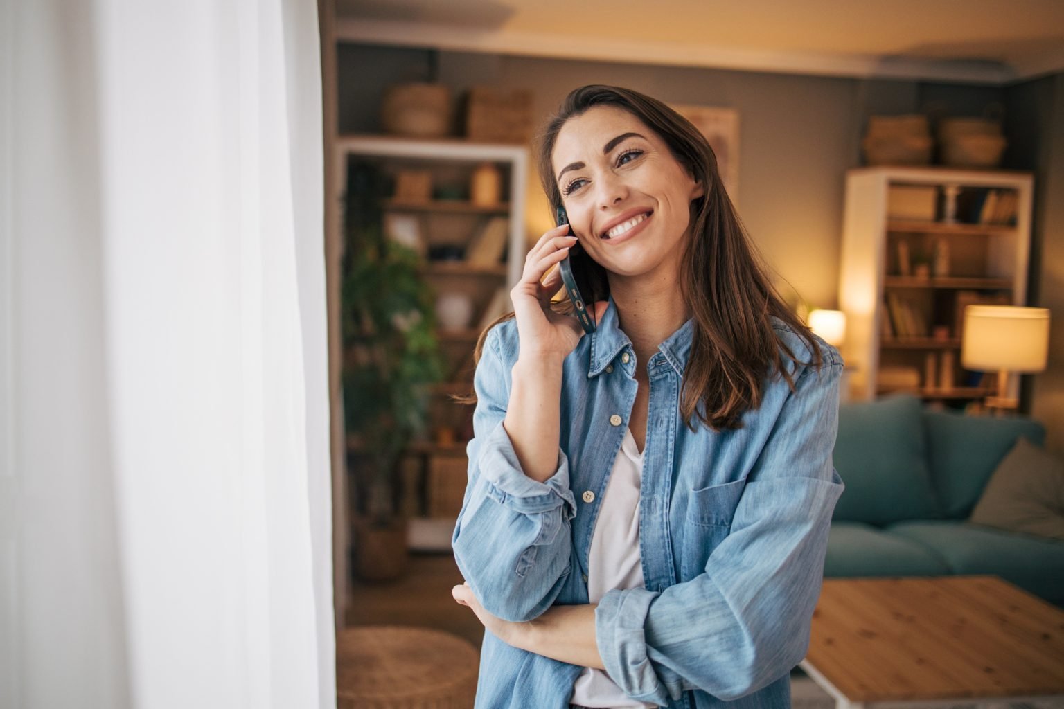 A woman on the phone in a comfortable, naturally lit home